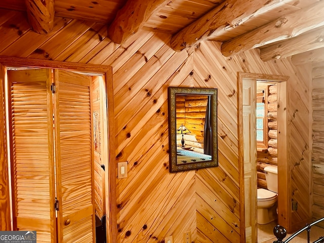 interior space with wooden ceiling, toilet, beamed ceiling, and wooden walls