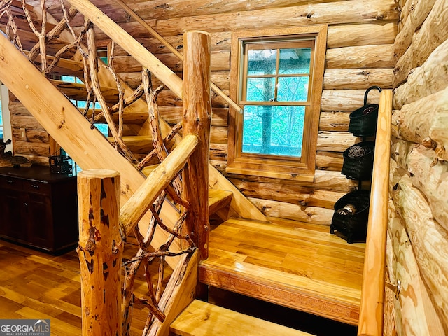 stairs with wood-type flooring and log walls