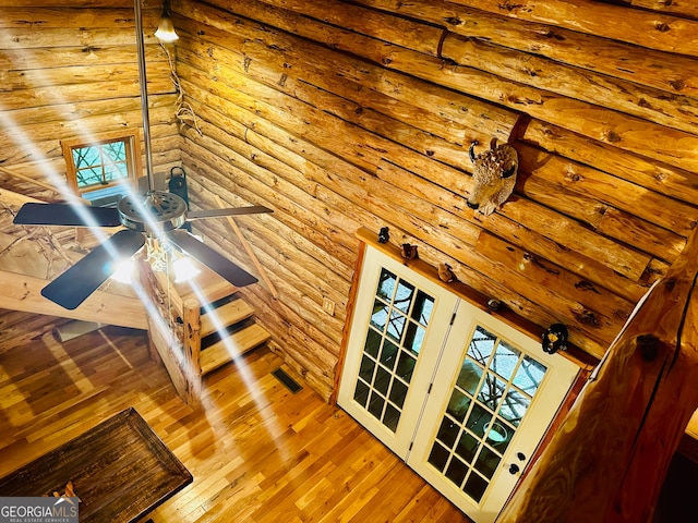 interior space featuring hardwood / wood-style flooring, rustic walls, and ceiling fan