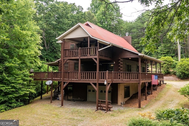 rear view of property with a wooden deck and a garage