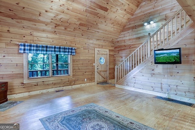 unfurnished living room with wooden walls, hardwood / wood-style floors, high vaulted ceiling, and wood ceiling