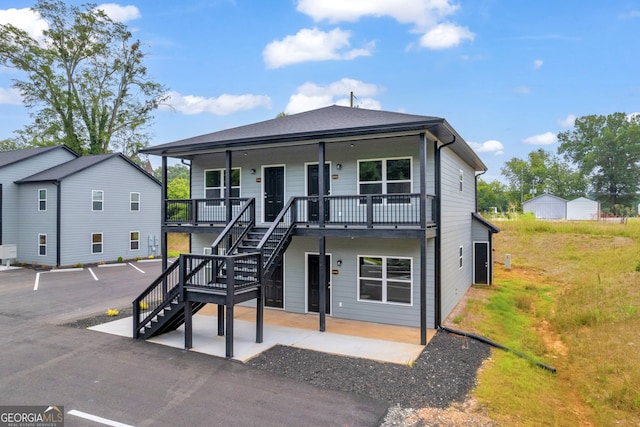 view of front of home featuring covered porch, stairs, and a patio