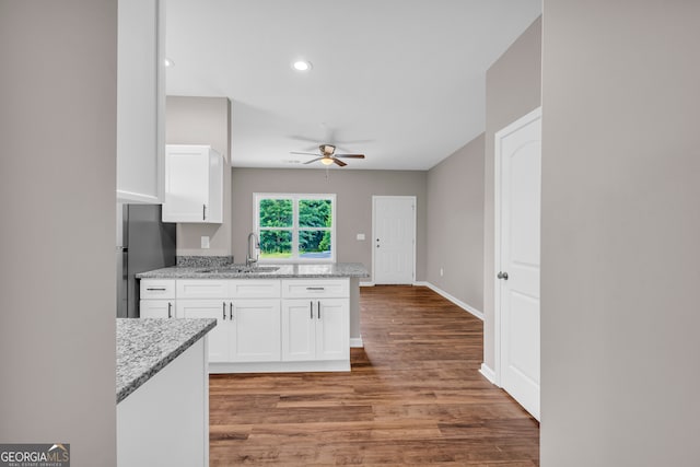 kitchen with hardwood / wood-style flooring, white cabinets, sink, light stone countertops, and ceiling fan