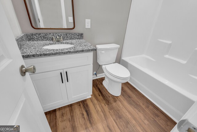 full bathroom with wood-type flooring, bathing tub / shower combination, toilet, and vanity