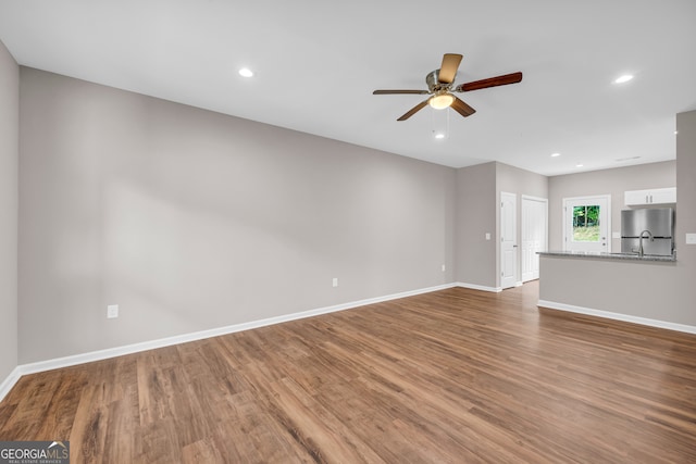 unfurnished living room featuring sink, ceiling fan, and hardwood / wood-style floors