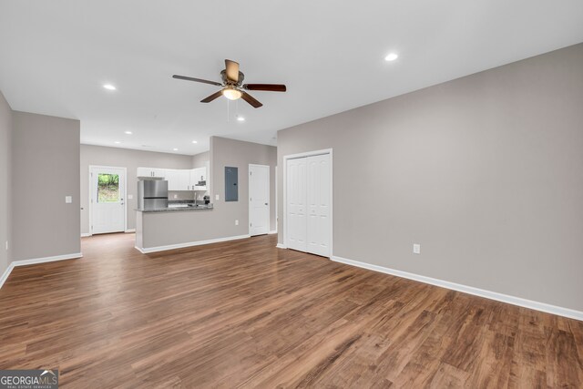 unfurnished living room with electric panel, wood-type flooring, and ceiling fan