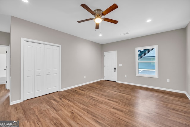 unfurnished bedroom featuring a closet, wood-type flooring, and ceiling fan