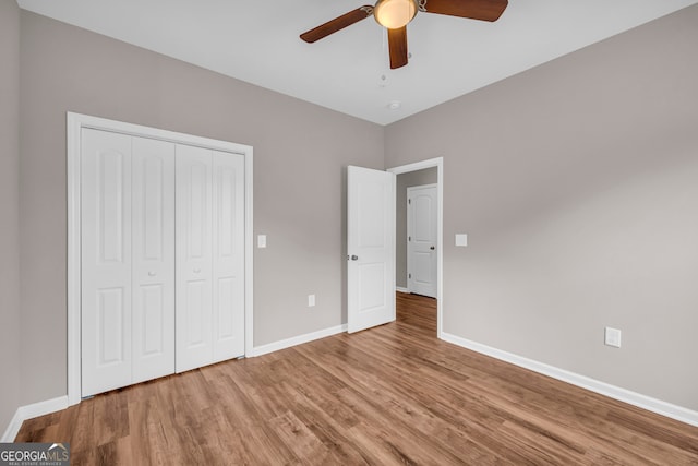 unfurnished bedroom featuring hardwood / wood-style flooring, a closet, and ceiling fan