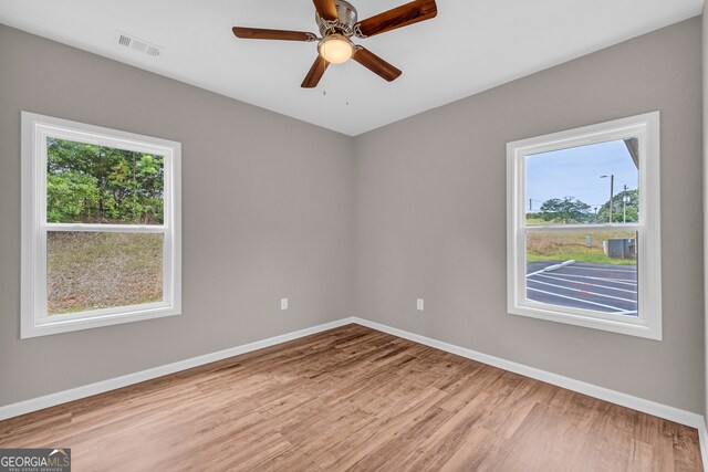 spare room with light wood-type flooring, ceiling fan, and a wealth of natural light