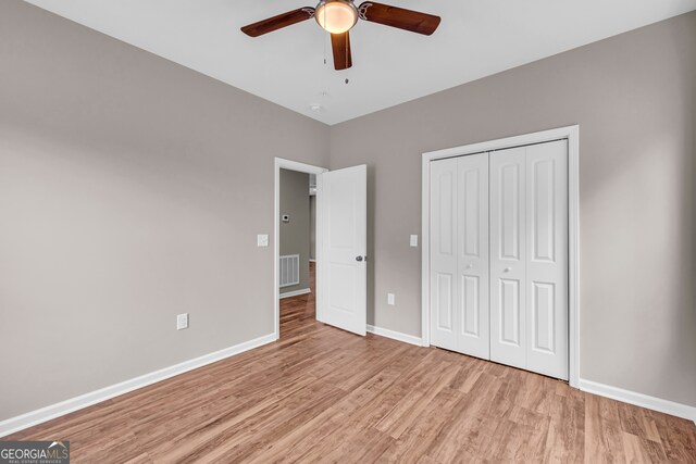 unfurnished bedroom with light hardwood / wood-style flooring, a closet, and ceiling fan