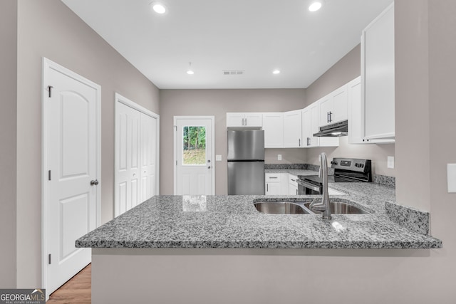 kitchen with kitchen peninsula, appliances with stainless steel finishes, light stone countertops, and light wood-type flooring