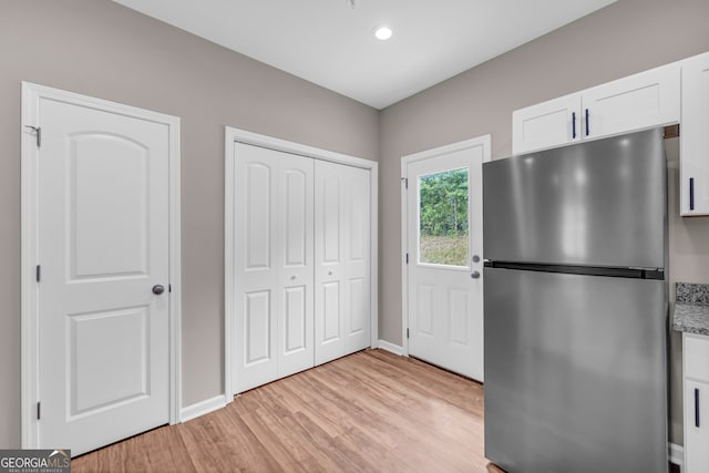 kitchen featuring stainless steel refrigerator, white cabinets, and light hardwood / wood-style floors