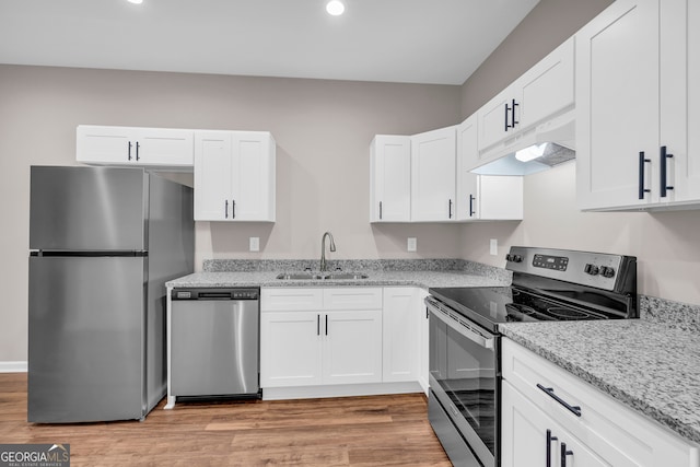 kitchen with premium range hood, white cabinets, light wood-type flooring, sink, and appliances with stainless steel finishes