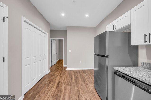 kitchen with white cabinets, dishwasher, light stone countertops, and light wood-type flooring