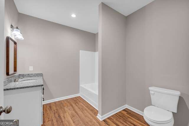 full bathroom with shower / bath combination, vanity, wood-type flooring, and toilet