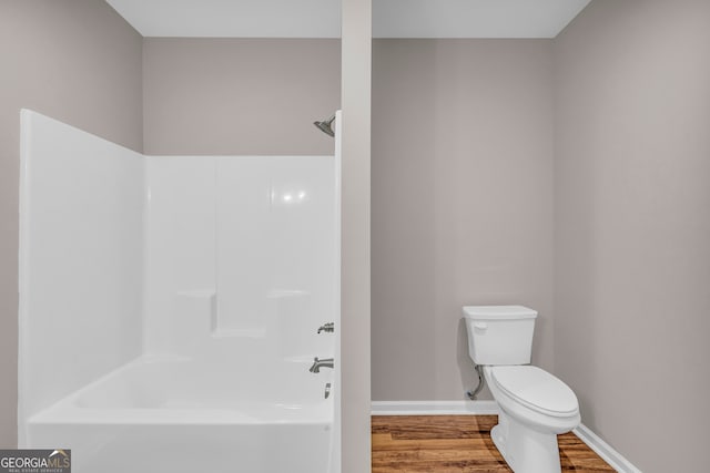 bathroom featuring wood-type flooring, toilet, and shower / bathing tub combination