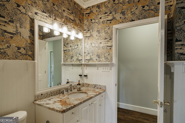 bathroom with ornamental molding, toilet, vanity, and wood-type flooring