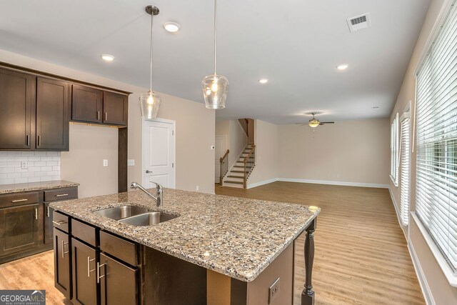 kitchen with backsplash, ceiling fan, sink, and light hardwood / wood-style flooring