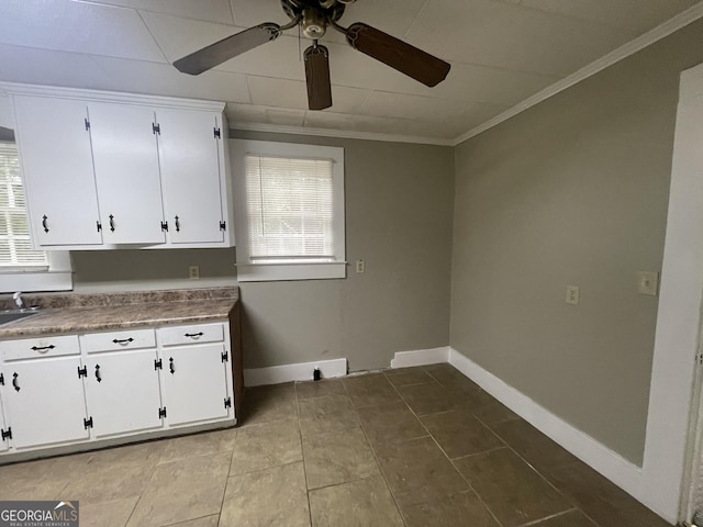 kitchen featuring sink, white cabinetry, crown molding, and light tile patterned floors