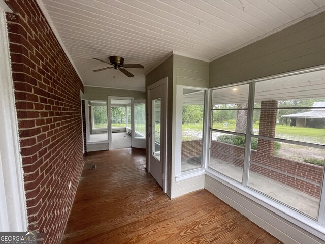 unfurnished sunroom featuring ceiling fan, plenty of natural light, and wood ceiling