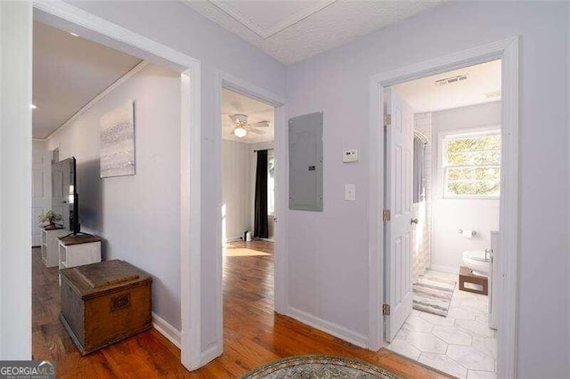 hallway with light wood-type flooring, electric panel, and baseboards