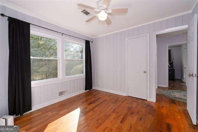 unfurnished bedroom with ornamental molding, visible vents, ceiling fan, and wood finished floors