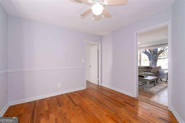 spare room with a ceiling fan, baseboards, and wood finished floors