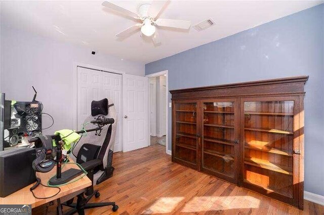 home office with light wood-type flooring and ceiling fan