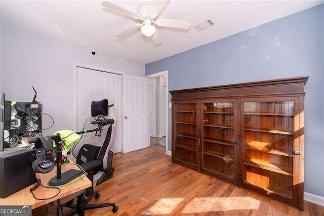 office area featuring a ceiling fan, visible vents, baseboards, and wood finished floors