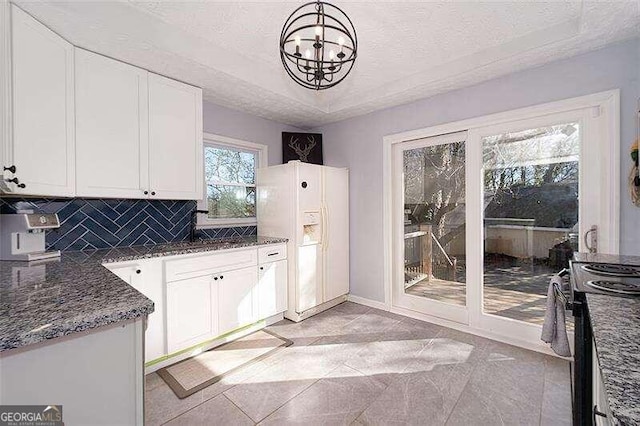 kitchen featuring black electric range, tasteful backsplash, white refrigerator with ice dispenser, and a textured ceiling