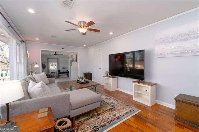 living room with hardwood / wood-style flooring, ceiling fan, and ornamental molding