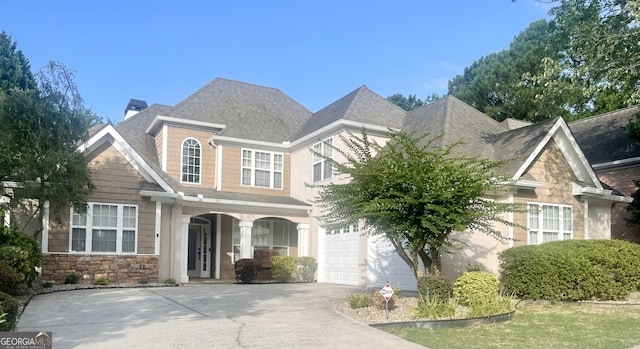 view of front of house with driveway, stone siding, a shingled roof, and a chimney