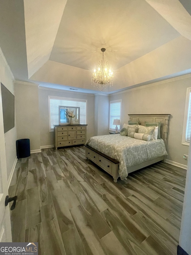 bedroom featuring a tray ceiling, crown molding, baseboards, and wood finished floors