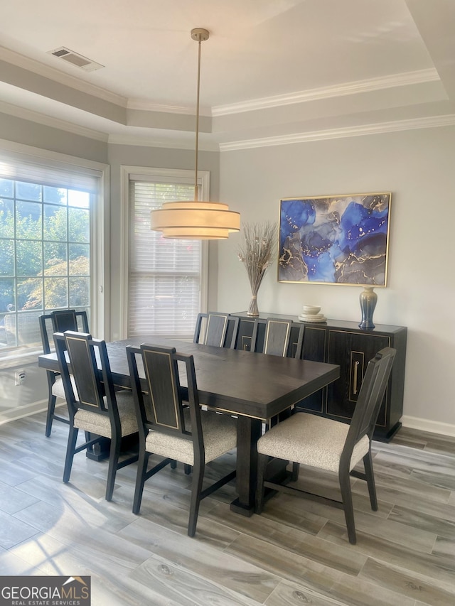 dining room with baseboards, a tray ceiling, visible vents, and crown molding