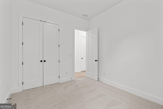 unfurnished bedroom with a closet and light carpet