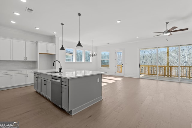 kitchen featuring sink, dishwasher, white cabinetry, tasteful backsplash, and an island with sink