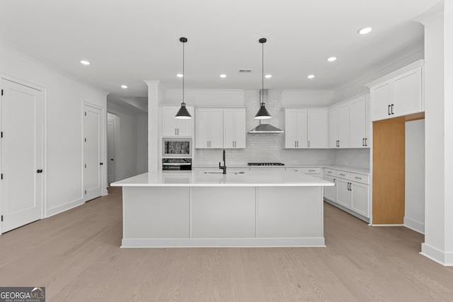 kitchen with white cabinetry, sink, hanging light fixtures, black appliances, and a center island with sink