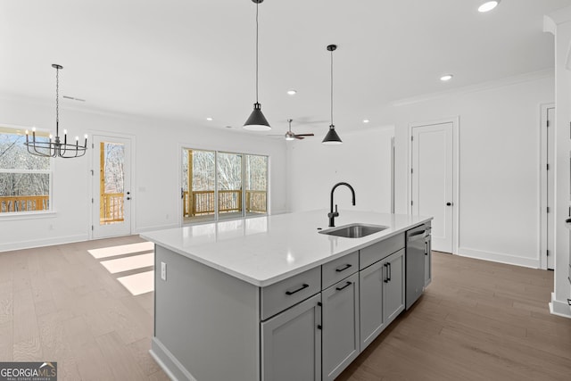 kitchen with sink, gray cabinetry, decorative light fixtures, dishwasher, and a kitchen island with sink