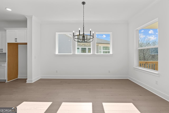 unfurnished dining area featuring crown molding, an inviting chandelier, and light wood-type flooring