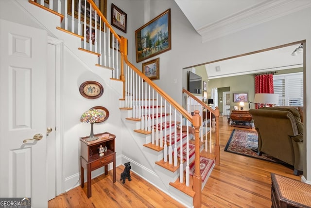 staircase featuring ornamental molding and hardwood / wood-style floors