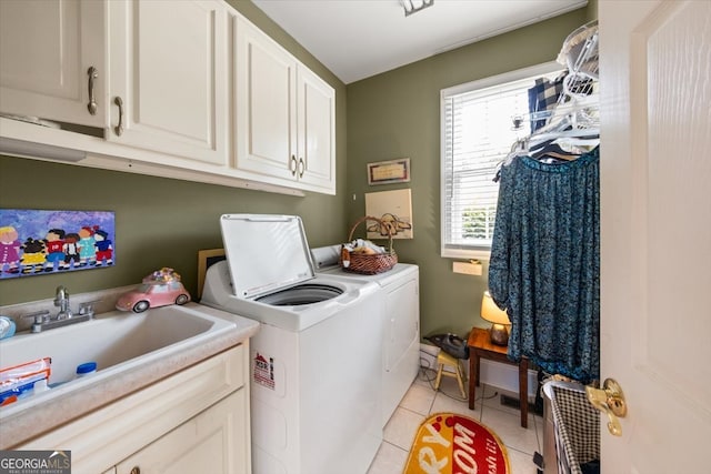 laundry area featuring light tile patterned floors, sink, washing machine and clothes dryer, and cabinets