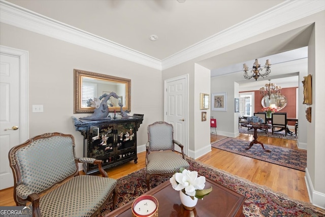 living area featuring a healthy amount of sunlight, ornamental molding, hardwood / wood-style floors, and a chandelier