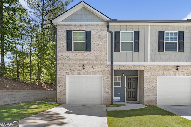 7041 Livia Pt, Riverdale, GA 30296 - townhome / multi-family property featuring a garage, driveway, board and batten siding, and brick siding