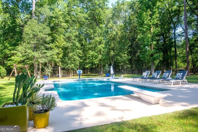 view of swimming pool with a patio area and a diving board