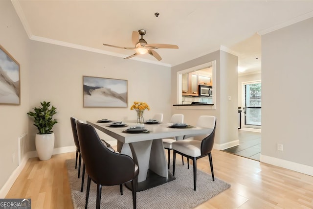 dining room with ceiling fan, crown molding, and light hardwood / wood-style floors