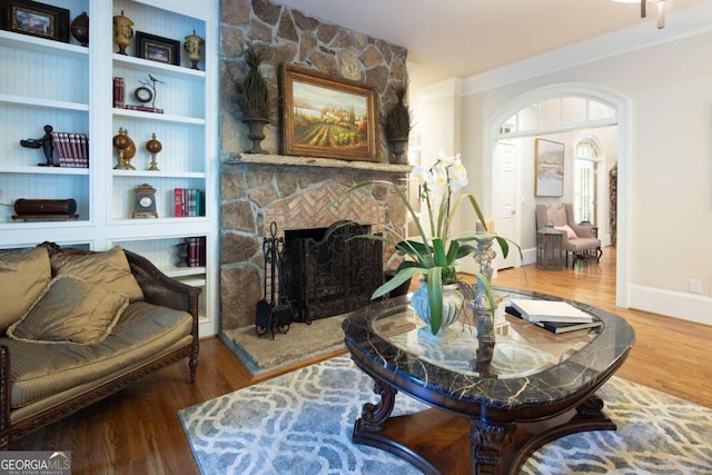 living room featuring wood-type flooring, a fireplace, and ornamental molding