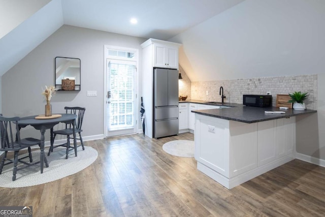 kitchen featuring white cabinets, backsplash, stainless steel refrigerator, and sink