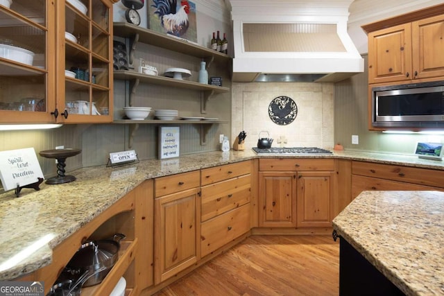 kitchen featuring premium range hood, decorative backsplash, light stone countertops, and stainless steel appliances