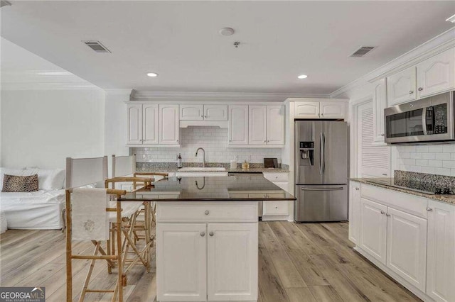 kitchen featuring ornamental molding, stainless steel appliances, and white cabinetry