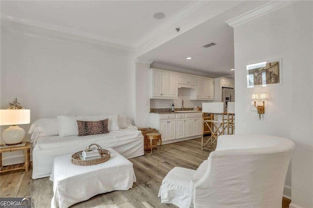 living room featuring ornamental molding, light hardwood / wood-style floors, and sink